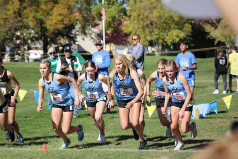 Girls Varsity team striding collectively as the gun goes off. Britt Prince and Ella Ford get in front of the pack first.