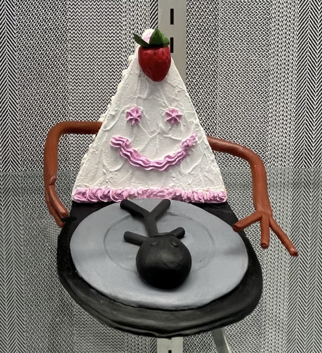 Dalia Khalafalla's cake project. Khalafalla sculpted a smiling cake that is about to eat a person who is on a plate.