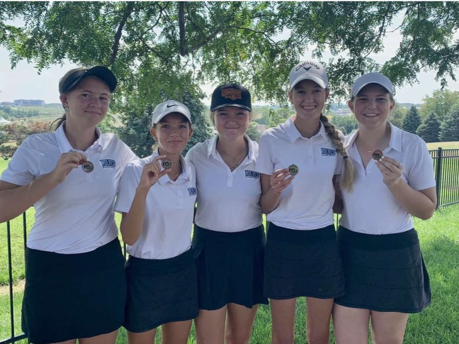The JV Girls Golf Team holding up their medals after a successful match. 