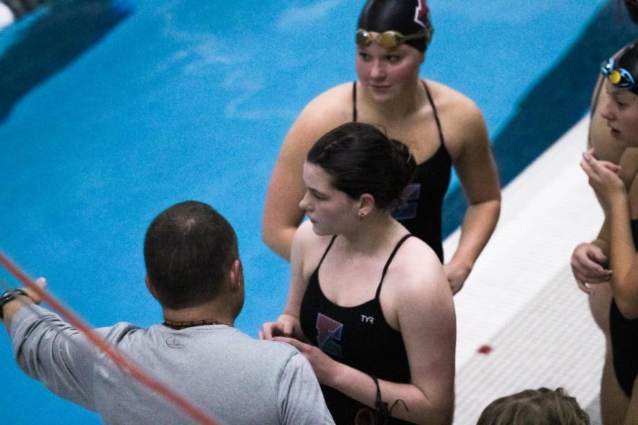 Junior Eva Reinoehl meets with her coach, Jay Thiltgen, before her race.  Reinoehl was preparing to swim in the 100 Freestyle Relay, 200 Freestyle Relay, the 200 Medley Relay, and the 50 Yard Backstroke at the duel versus Bellevue West on Tuesday December 5th.  