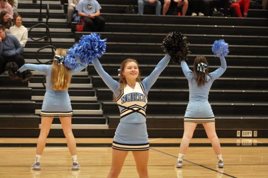 Chloe Reinhardt waves her pompoms in the air during the cheer performance at the pep rally. Reinhardt smiles at the crowd while cheering.