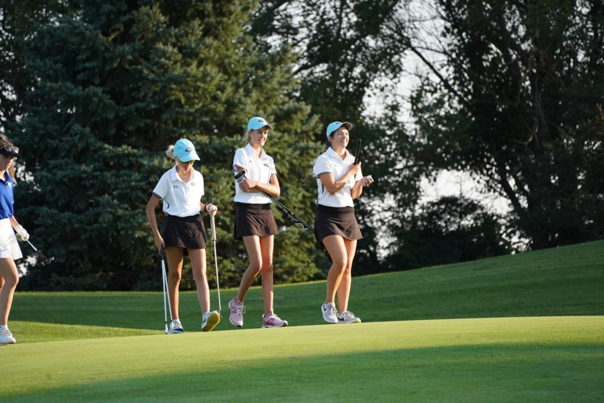 Seniors Sharlan Skrupa and Shea Meridith talk with Junior Chelsea Mahloch while walking off the green. 