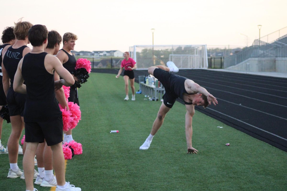 Senior Tyler Murphy attempts a cartwheel on the sidelines during powder puff September 13, 2023. He plays on varsity football. 
