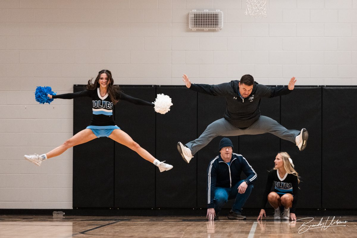 Senior Delaney Bott and Social Studies teacher Anthony Dunn mid-air as they preform a cheer. Each teacher and cheerleader duo choreographed an eight count to preform at the winter pep rally on Dec. 8th 2023.