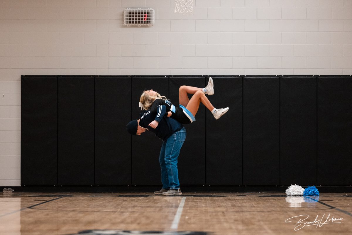 English teacher Jeff Lacey flips senior Maya Schmeeckle. Each teacher and cheerleader duo choreographed an eight count to preform at the winter pep rally on Dec. 8th 2023.
