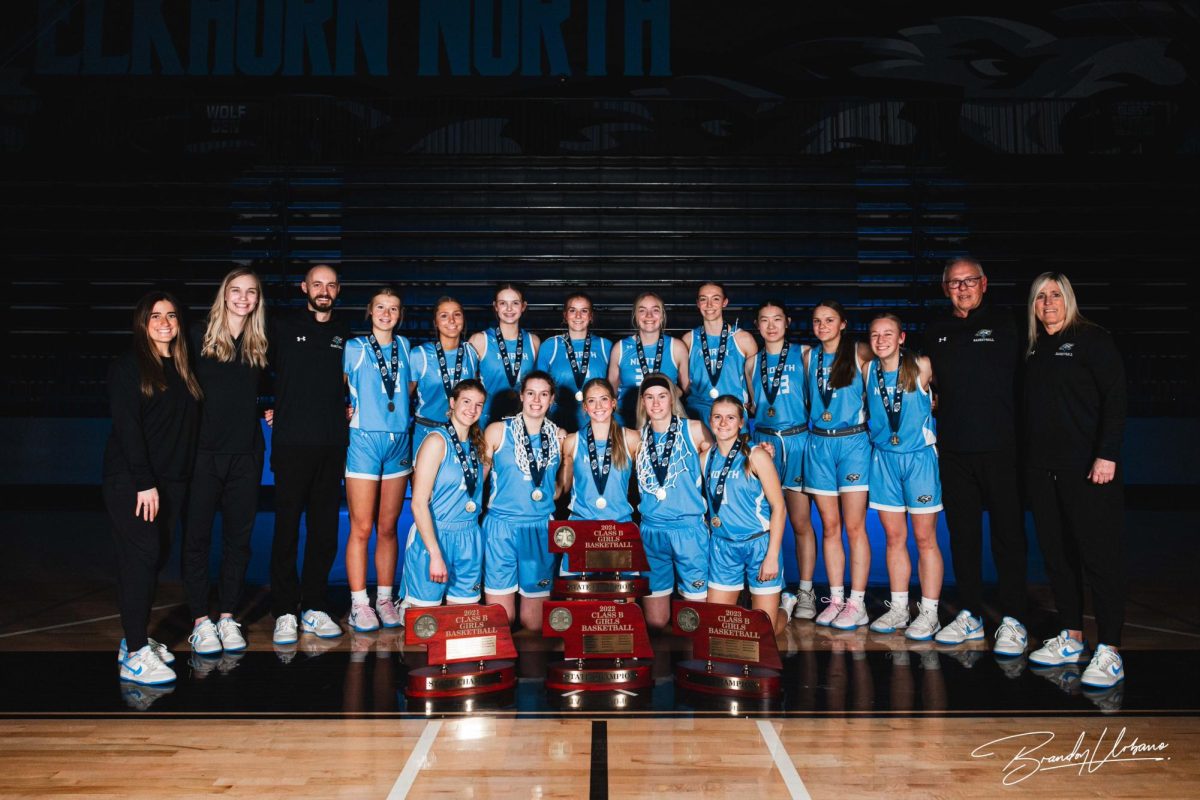 The girls basketball team standing around their four consecutive state champion trophies. This was shortly after the Wolves defeated Skutt Catholic High School in the Nebraska Girls Basketball State Championship on March 2nd, 2024.