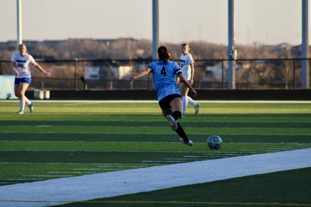 Senior Ava Spies (4) kicks the ball into the field towards the goal in the first half on April 4, 2024. The ball gets passed to Hannah Nossal in attempt to get closer to the goal.