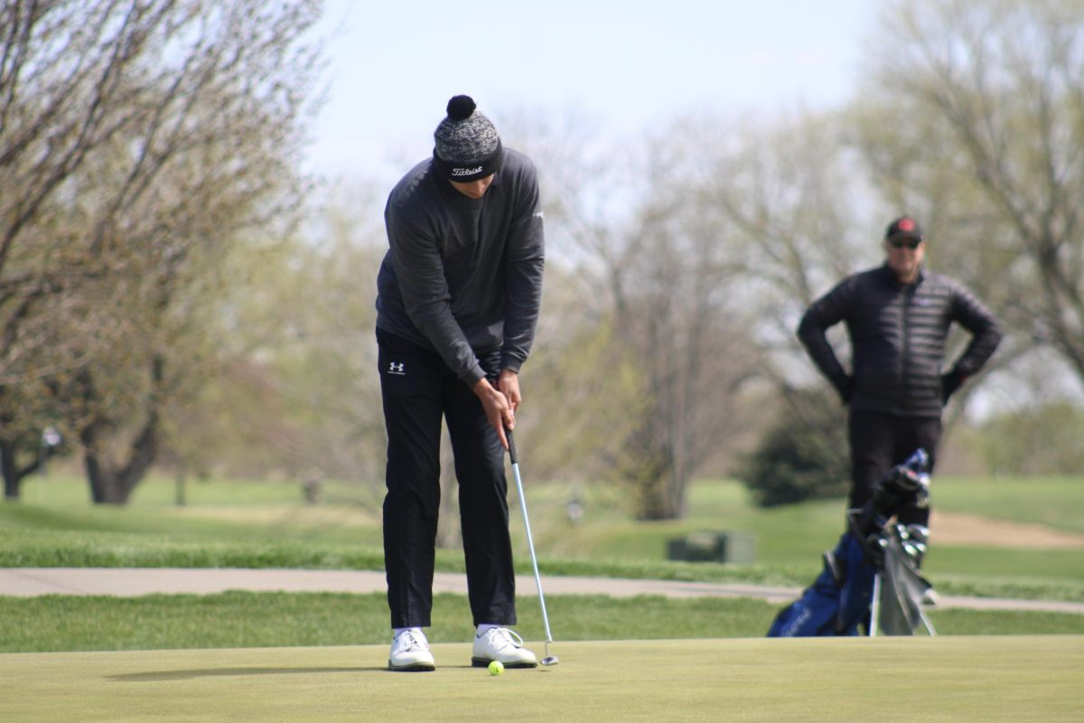 Nathan Kudrna (11) takes a practice swing before his final putt of the day at River Wilds on April 19, 2024. He then watches his teammates finish the round.