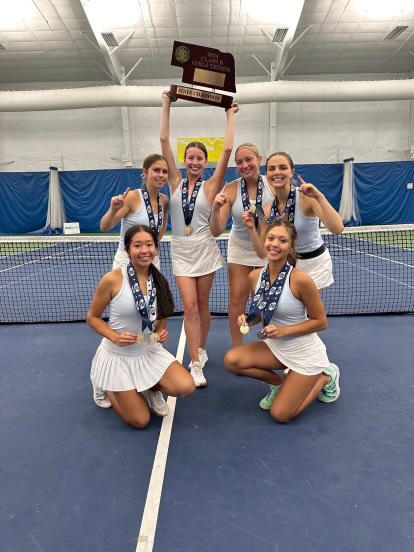 Haylee Wolf (12) holding the girls tennis state champion trophy surrounded by her teammates. This was the third consecutive state championship for the Elkhorn North Girls.