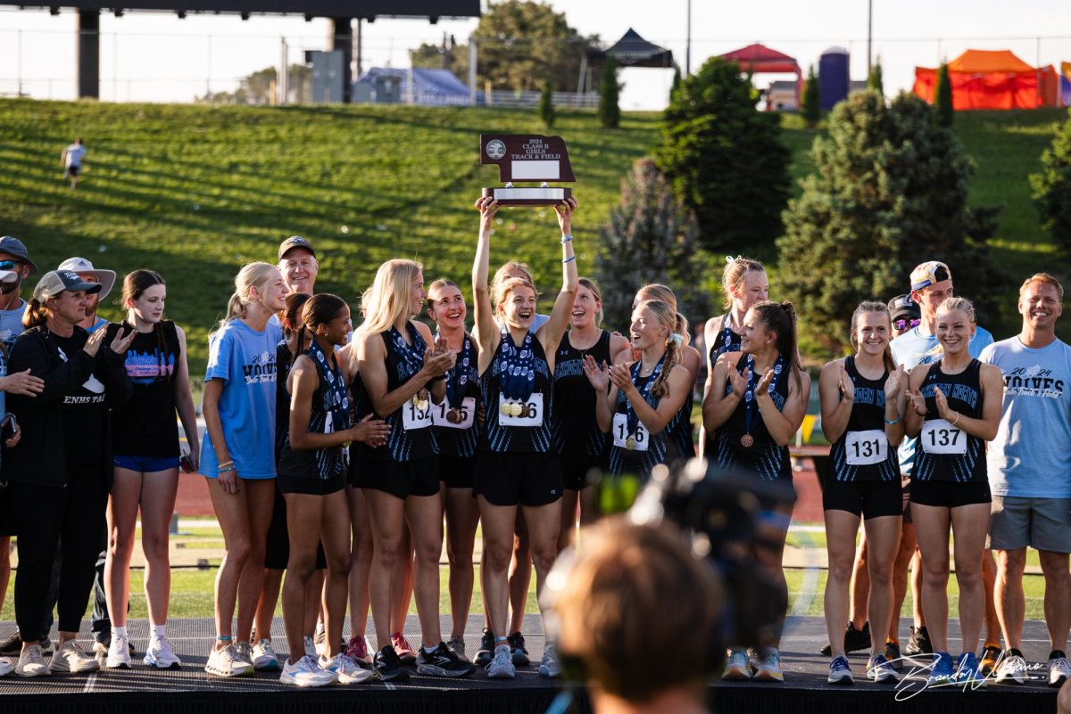 Sydney Stodden (12) holds state runner-up trophy. She is surrounded by her teammates celebrating their win. 