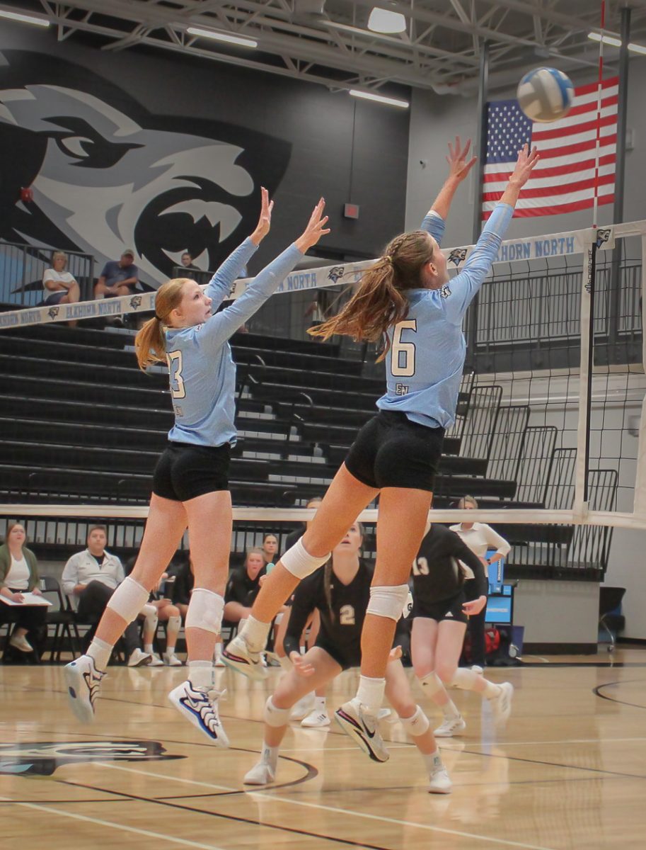 Freshman Payton Palmer (13) and Junior Hayden Booth (6)  jump in an attempt to block the ball. Booth was able to get the block.