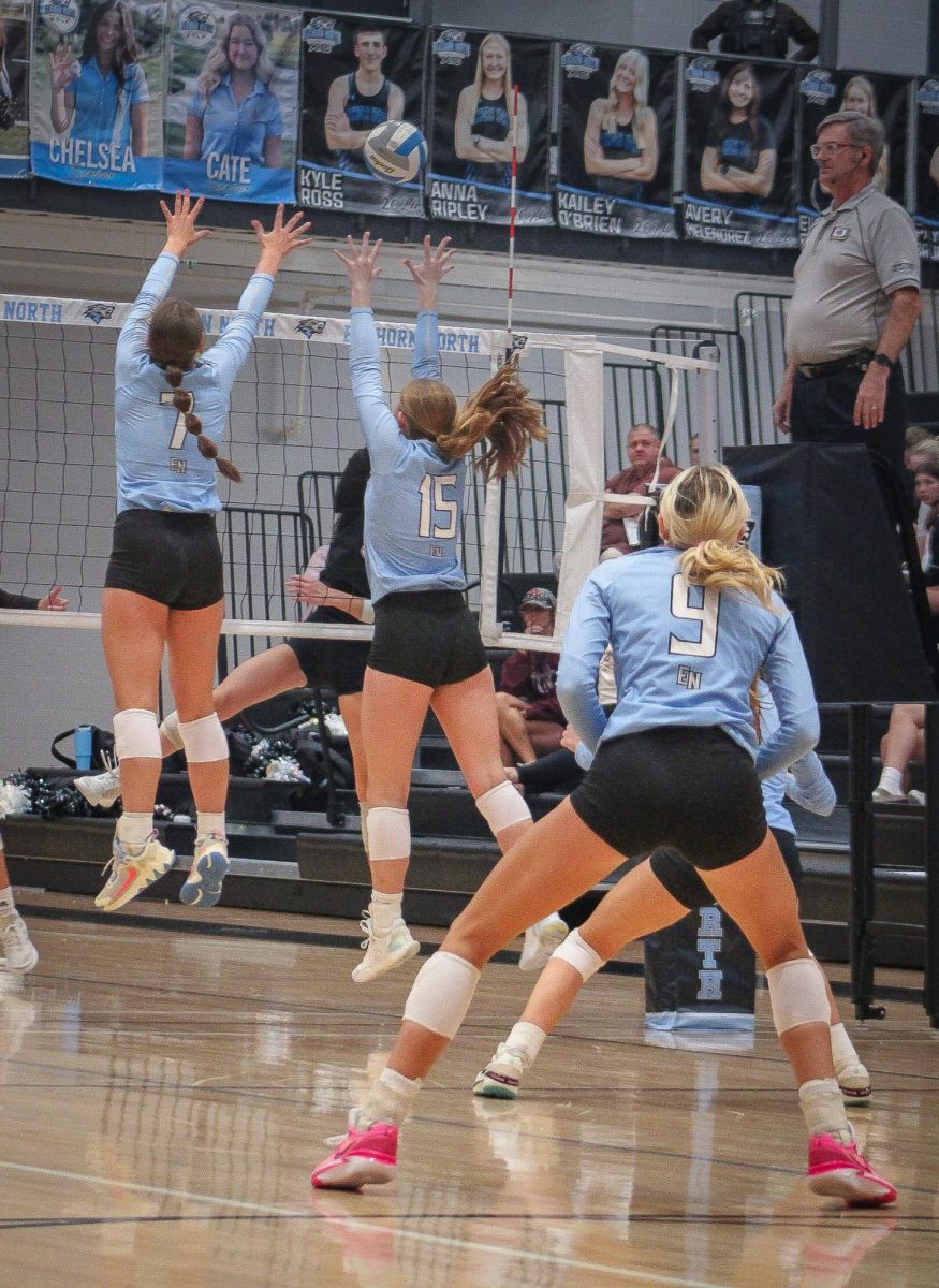 Senior Lindsey Hrbeck (7) and Sophomore Kaitlyn Huff (15) leap to block the ball. Sophomore Reagan Walraff (9) was ready to make a pass.
