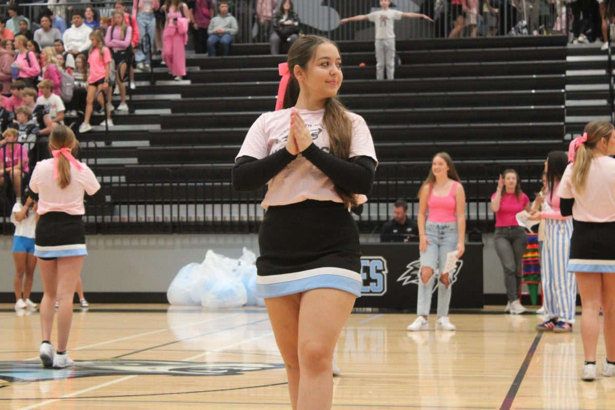 Senior Anne Anicio de Magalhaes on the cheer team waits as students arrive on the gym bleachers. Anicio de Magalhaes performed their warm up routine while they cheer and dance team patiently waited for all high schoolers and teachers. 