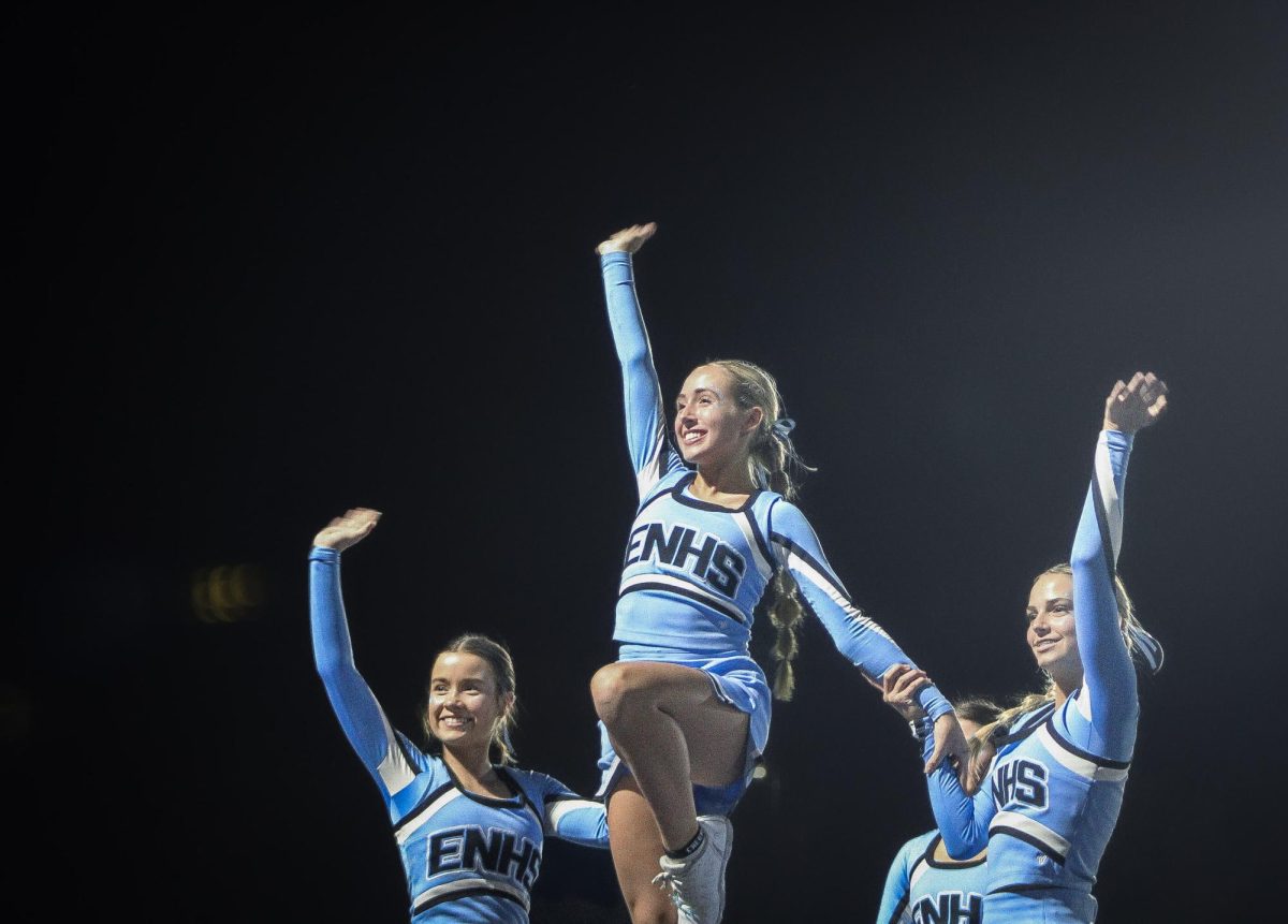 (Left to right) Junior Ella Jackson, Junior Vanessa Miller, and Freshman Violet Kunz wave to the Elkhorn North High School student section. Jackson is a cheer captain.