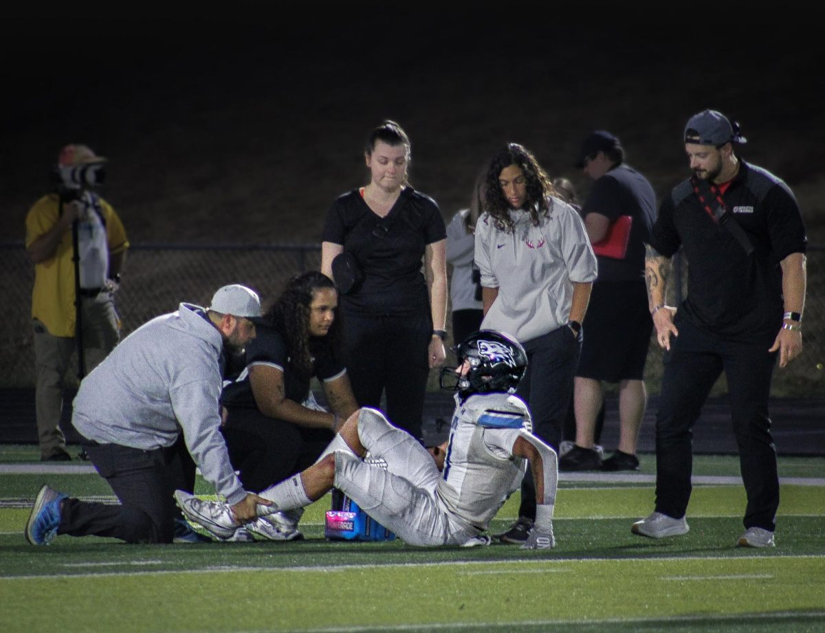 Athletic trainers check Senior Nathan Kudrna (11). He injured his right ankle late in the first quarter.