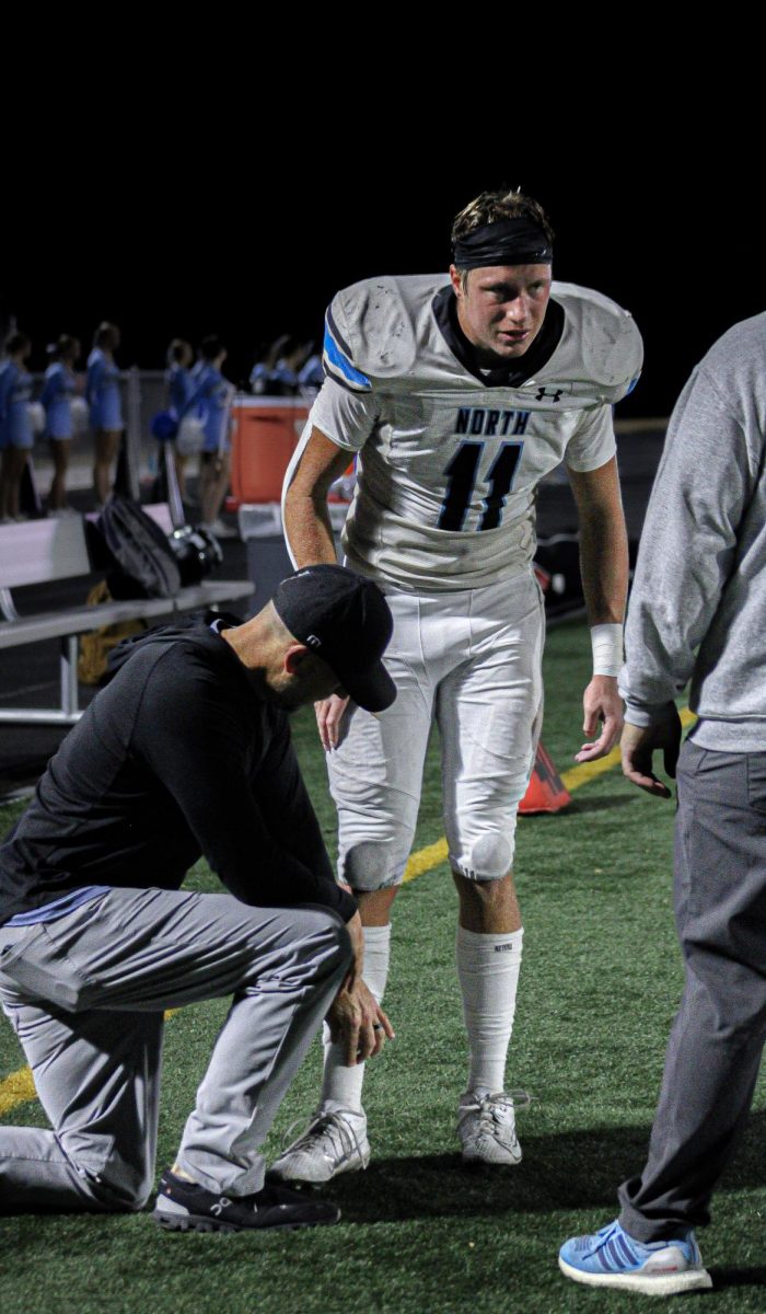 Senior Nathan Kudrna (11) listens to his coaches after he was taken off the field. They told him he’d be sitting out for the rest of the game, and possibly the rest of the season.