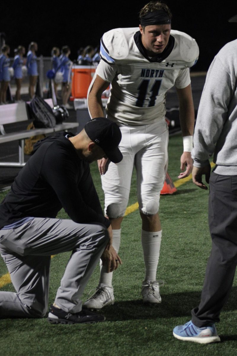 Senior Nathan Kudrna (11) listens to his coaches after he was taken off the field. They told him he’d be sitting out for the rest of the game, and possibly the rest of the season.
