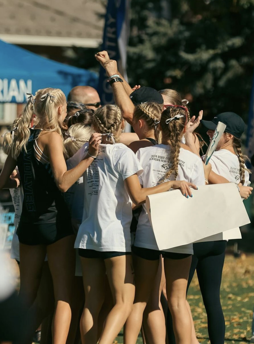 The Wolves celebrate around head coach Jordan Fuglestad after winning state cross country championship. Photo courtesy of Alden McKnight.