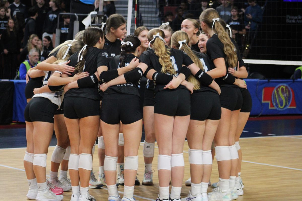 Volleyball players huddle and discuss a play. The girls stood together and spreaded positive advice. 