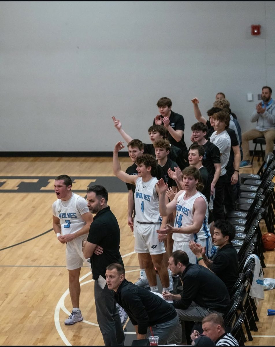 Boys basketball cheers on the team hitting a three when they are up in a game. The shot was taken in a game against the Hastings Tigers when most of their starters came out so the bench could play.
