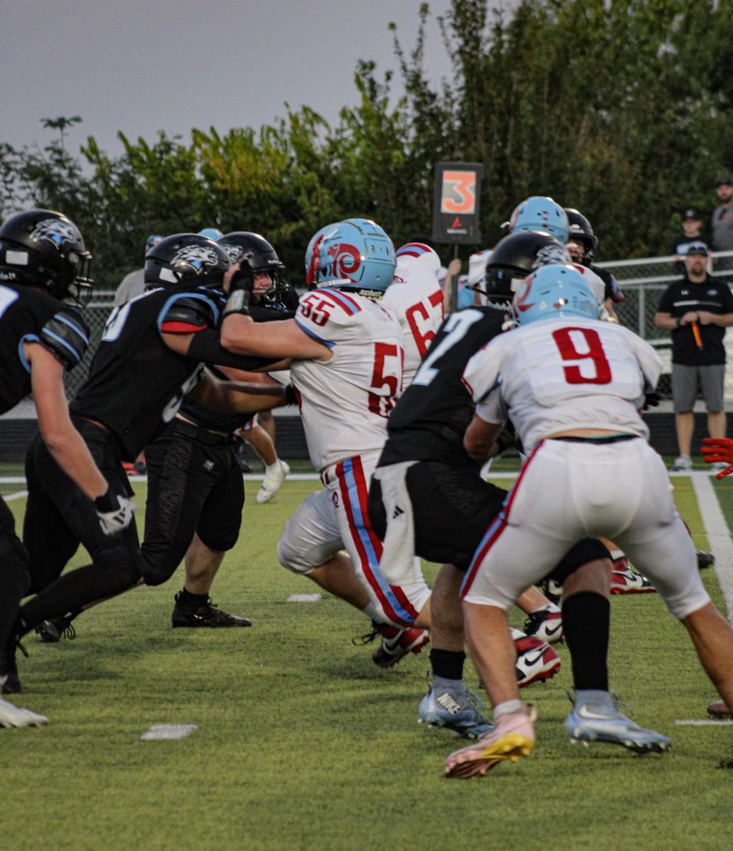 Senior Christian Schlott rushes the ball as he engages with the defensive linebacker. Schlott later played in the halftime show as well.