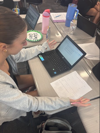 Bella Smith being conflicted over doing homework with a computer or paper and pencil. 