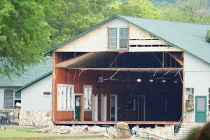 A full wall is missing from a Camp Mystic building after the Texas floods. The building is located near the Guadalupe River, where water rose over 20 feet during the flooding and affected many other buildings on camp property. Photo courtesy of Julio Cortez and AP Photo.