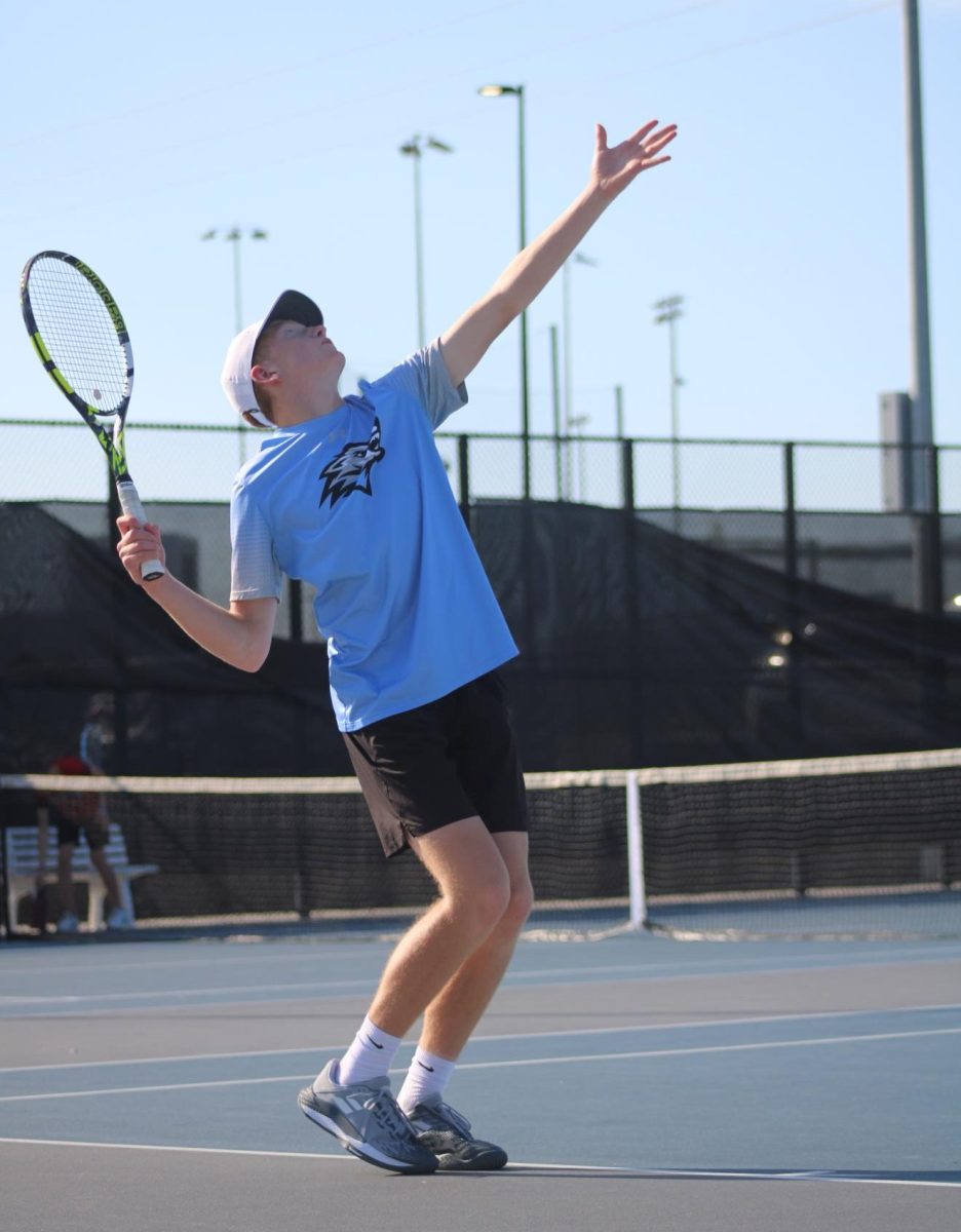 Freshman Jake Renes tosses the ball and prepares to serve to his opponent. Renes competed in a singles match and a doubles match with his partner, Jack Pierson.
