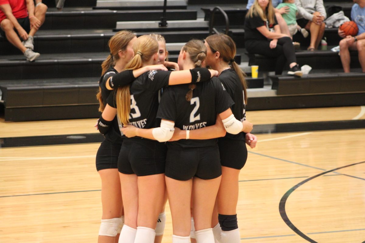 Players huddle on the court after a timeout to talk more about the game. It was near the end of a competitive set so they used their time to discuss strategy. 