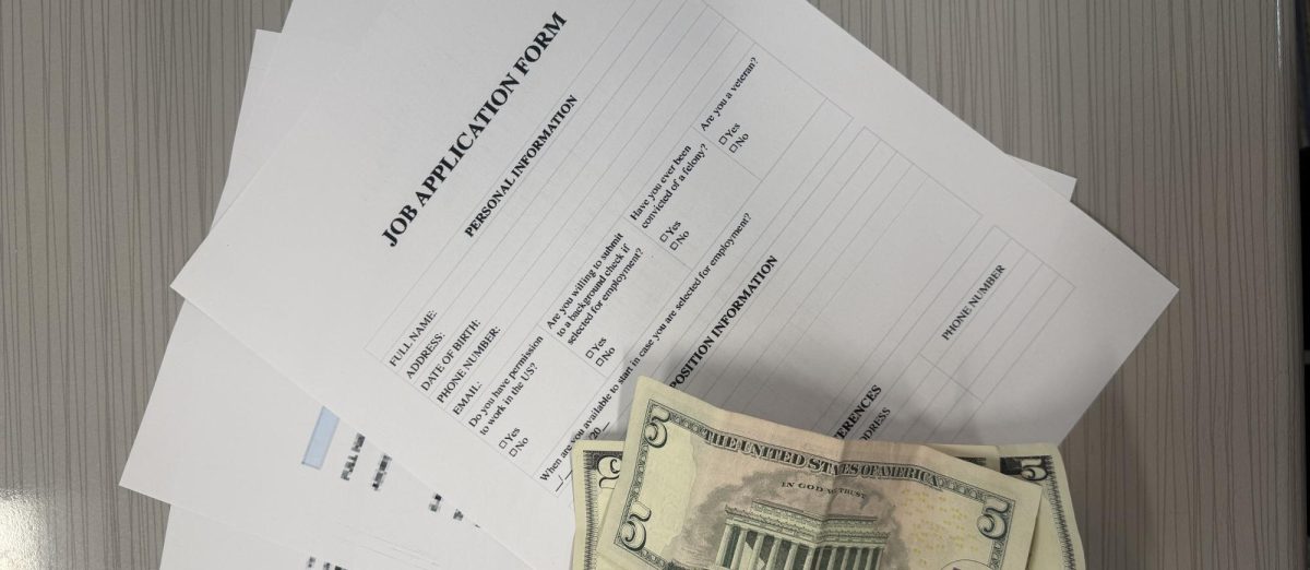Image of multiple job applications beside a stack of cash.