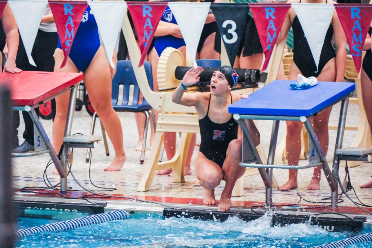 Senior Jenna Polking sitting near the edge of the water at Rams Relay 2025. Polking led her team to another great performance on the season.