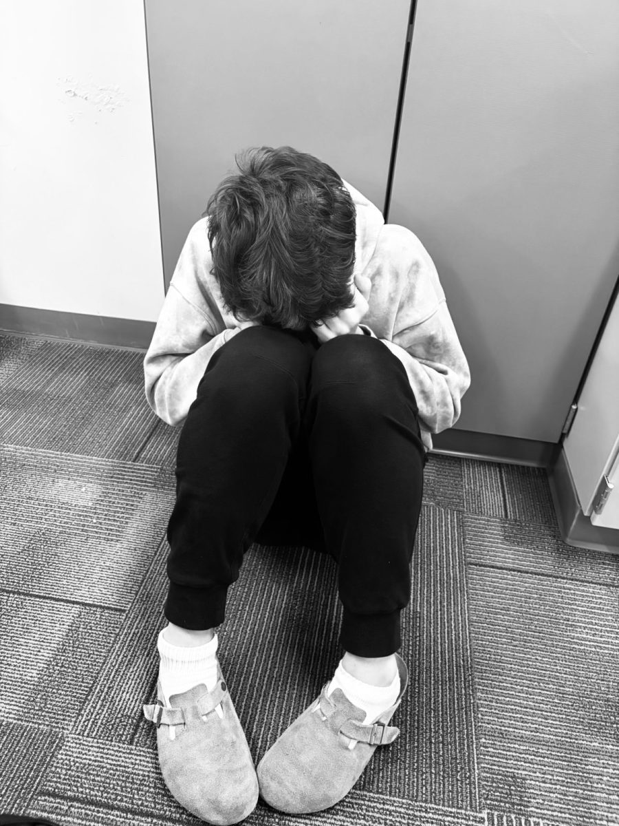 ENHS student sitting in the corner thinking. This student is sad and needs someone to talk to in this hard moment in their life. 