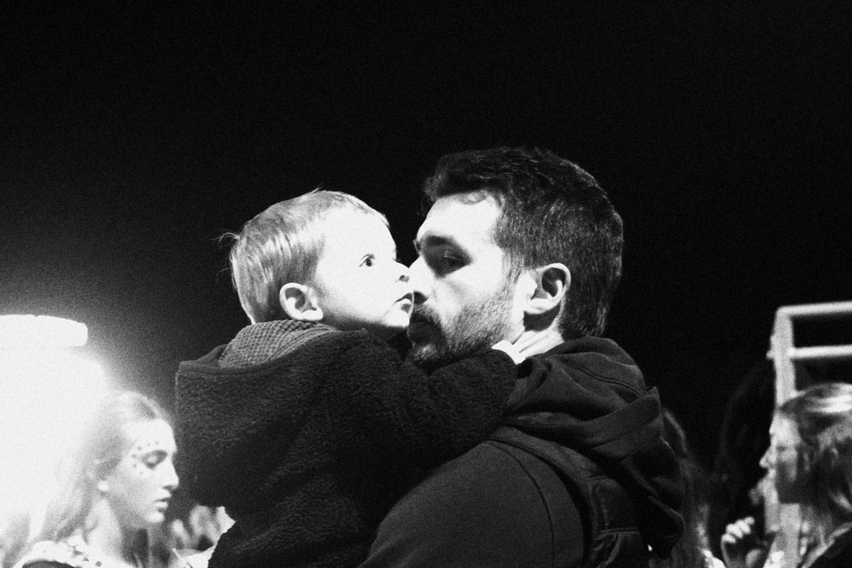 English teacher Colton Schneider holds his child at a football game. At the football games he cheered on his students and wife while parenting his son. 
